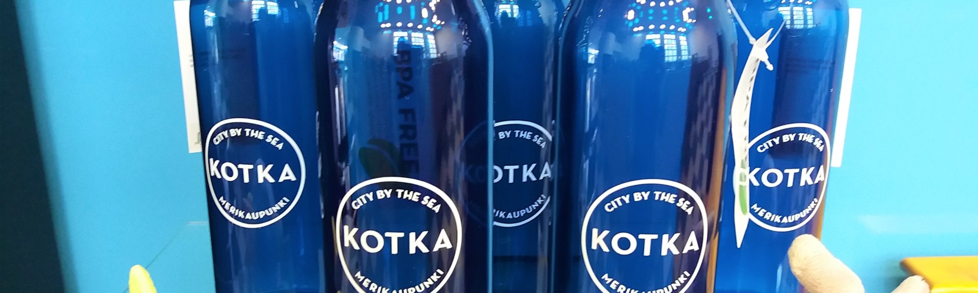 Kuvassa on Kotka-tuotteita, eli juomapullo ja pehmohahmo.