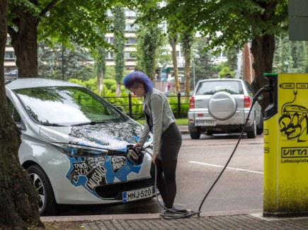 Nainen lataa Kotkan kaupungin sähköautoa Sibeliuksenpuiston parkkipaikalla