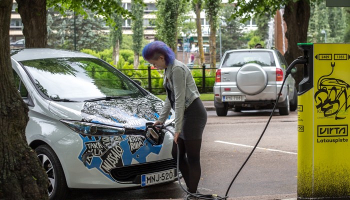 Nainen lataa Kotkan kaupungin sähköautoa Sibeliuksenpuiston parkkipaikalla