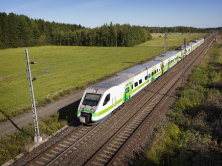 Kuvassa pendolino juna matkaa raiteilla kesäisessä maisemassa