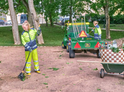 Kuvassa kesätyöntekijät haravoimassa