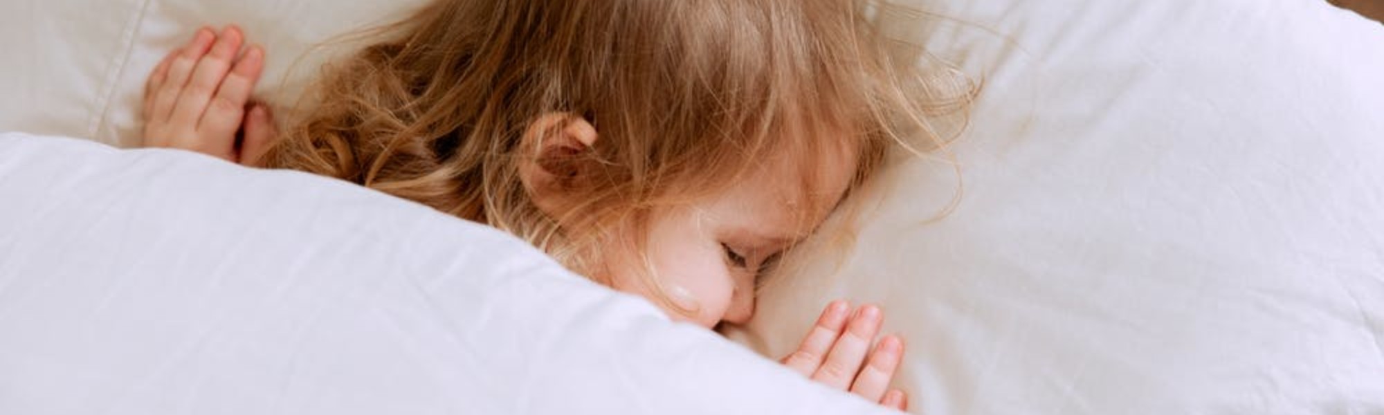 Kuvassa näkyy peiton alla nukkuvan lapsen pää tyynyllä.