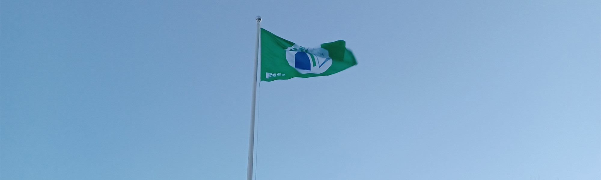 Vihreä lippu liehuu sinisellä taivaalla.