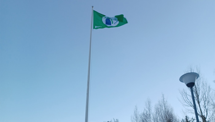 Vihreä lippu liehuu sinisellä taivaalla.