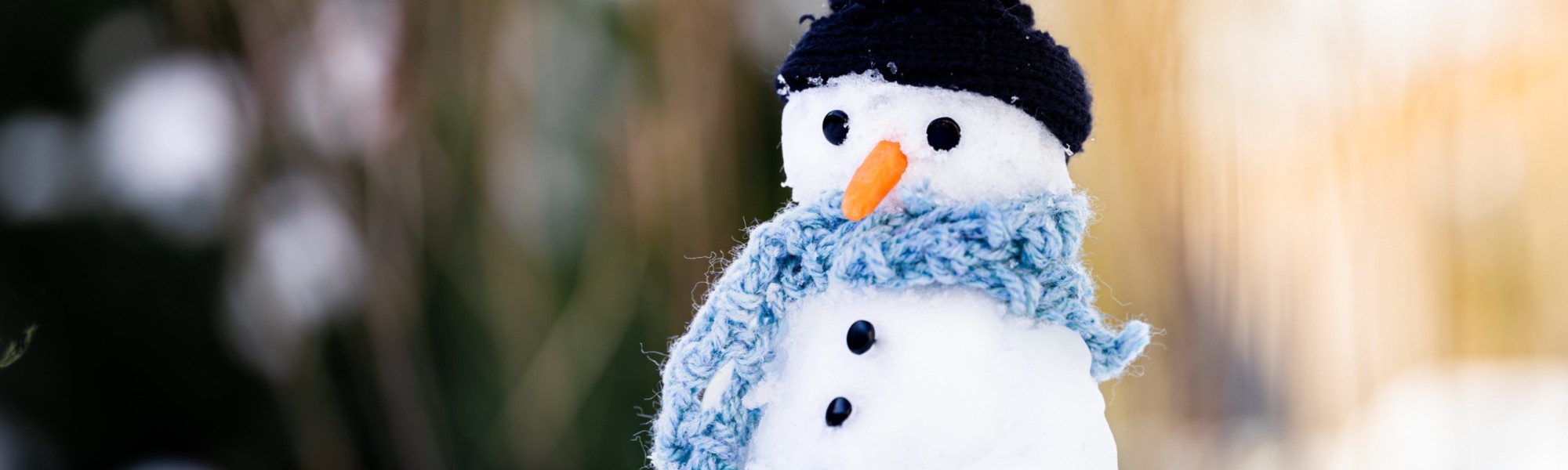 Lumiukolla on musta pipo ja vaaleansininen kaulaliina.