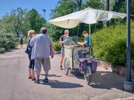 Pop up -jäätelökioski Sapokassa. Myyjä ja kolme asiakasta.