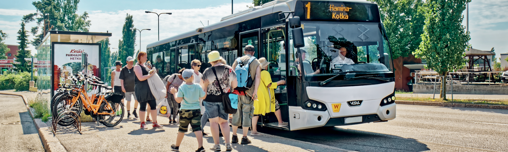 Kuvassa ihmisiä on nousemassa linja-autoon Karhulan linja-autoasemalla.