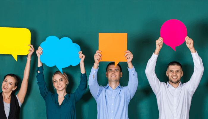 Kuvassa aikuisia jotka pitävät kädessä erivärisiä puhekuplia