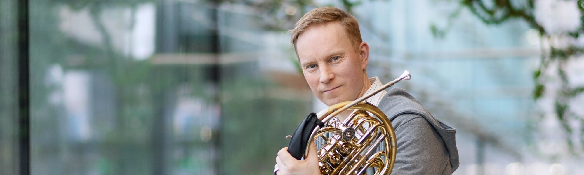 Jukka Harju istuu pöydällä soitin kainalossa.