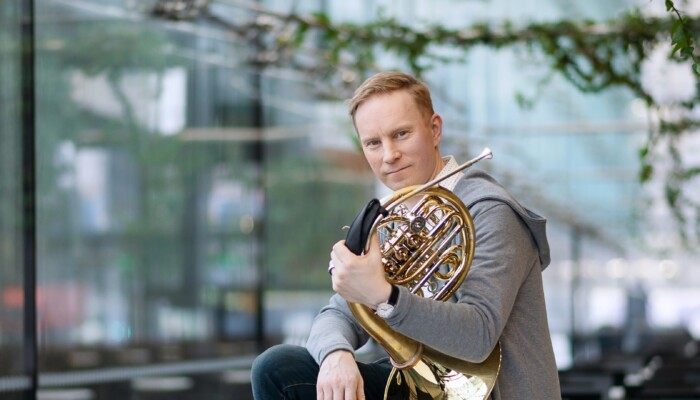 Jukka Harju istuu pöydällä soitin kainalossa.