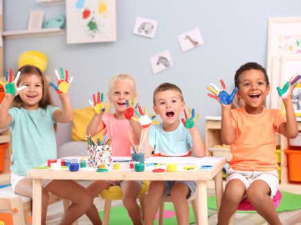 Iloisia lapsia maalaamassa sormiväreillä