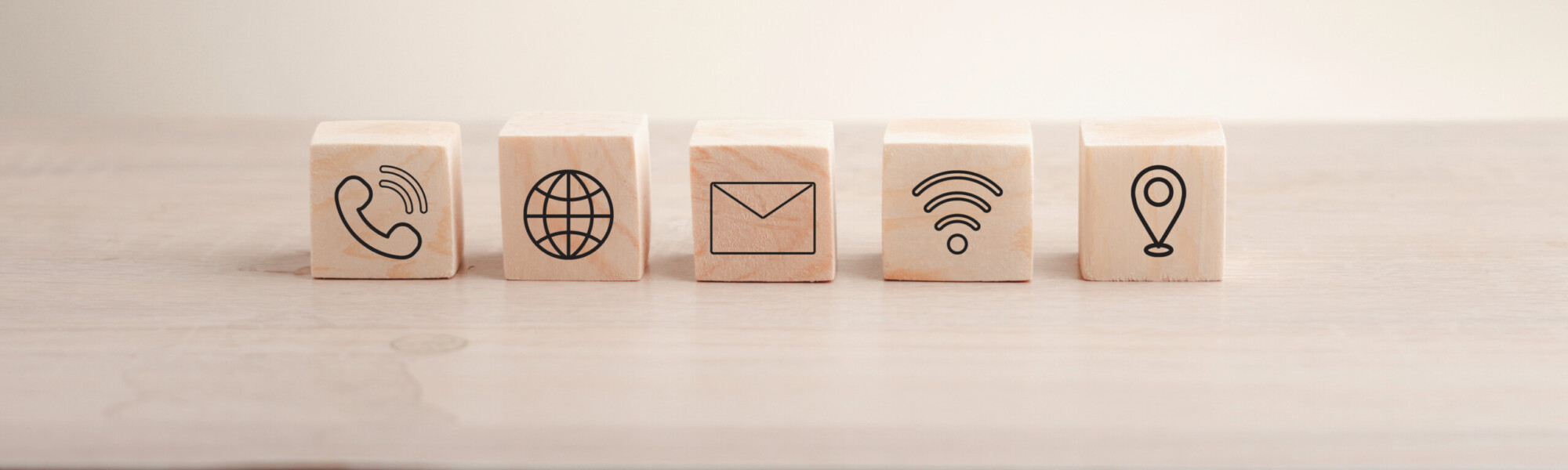 Puinen kuutiopalikka, jossa on viestinnän, sähköpostin, osoitteen ja Wi-Fi:n ikonit. Verkkosivun 'Ota yhteyttä' -osio tai sähköpostimarkkinoinnin konsepti. Hakukonsolin käyttö verkkosivustosi kanssa."