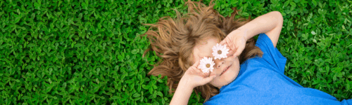 lapsi nakaa nurmikolla silmissä päivänkakkaran kukat