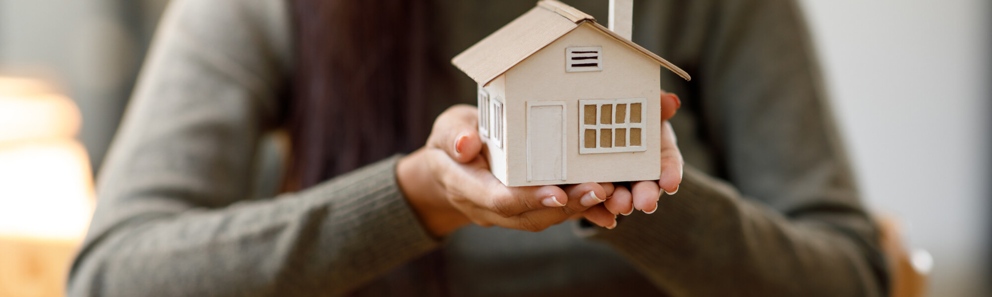 ihmisen kädessä on valkoinen omakotitalo