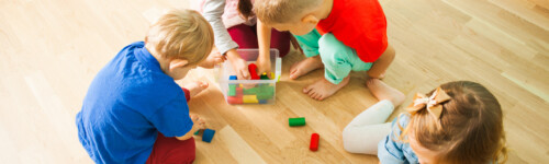 lapsia lattialla leikkimässä värillisillä palikoilla