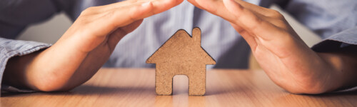 miehen kädet ovat talo silhuetin päällä