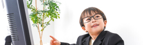 pieni lapsi puvuntakki päällä kirjoittaa tietokoneella