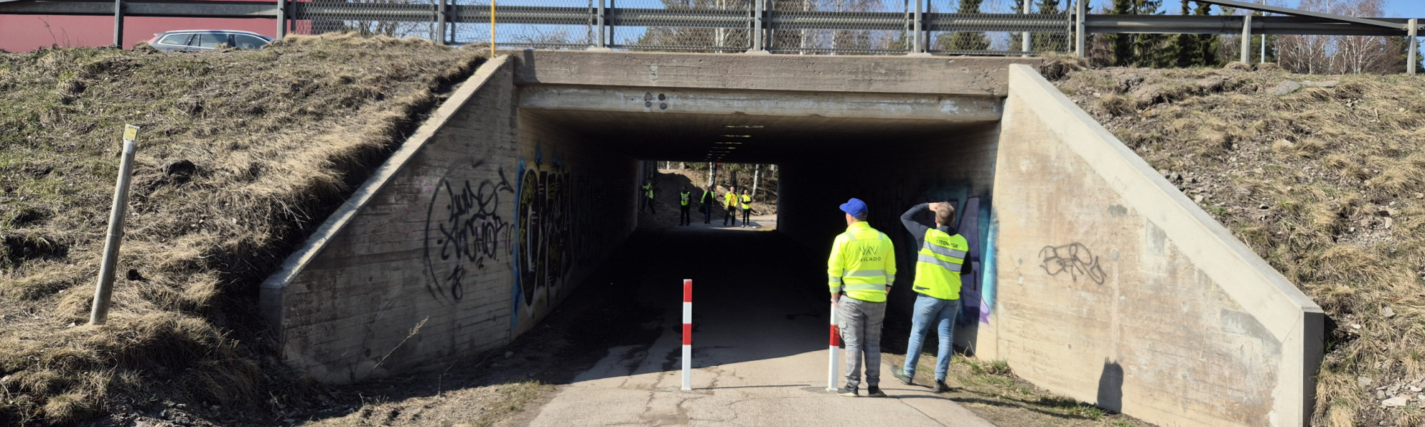 Sillan akka kulkeva alikulkutunnelli. Tunnelin edustalla kaksi työvaatteisiin pukeutunutta henkilöä.